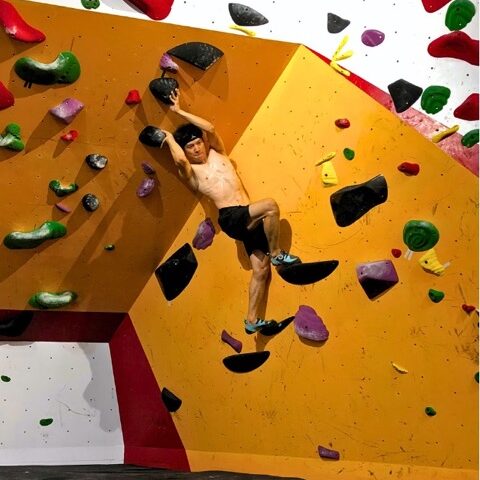 Man awkwardly climbing a bouldering route in the cave of Hanoi Climbing Hub, Long Bien, Vietnam